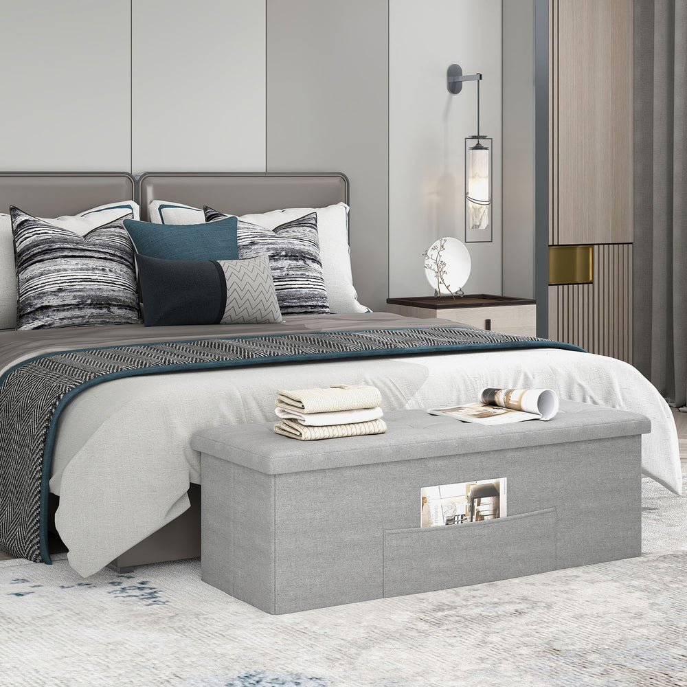 Light gray folding storage ottoman bench with padded seat, 43 inches, ideal for bedroom or living room organization.