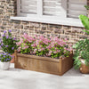Rectangular brown planter box made of natural fir wood, featuring drainage holes, filled with pink flowers for garden.