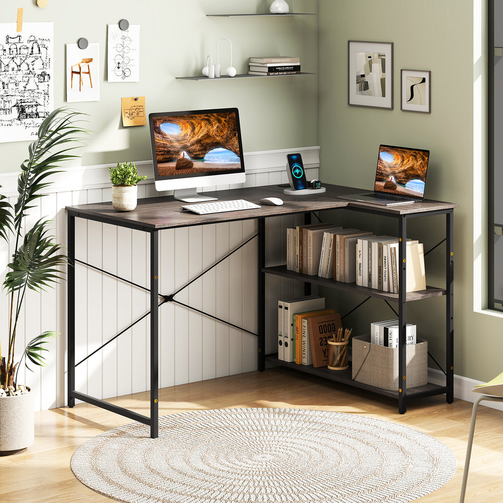 Reversible L-shaped computer desk with gray finish, featuring an adjustable shelf and compact design for small spaces.