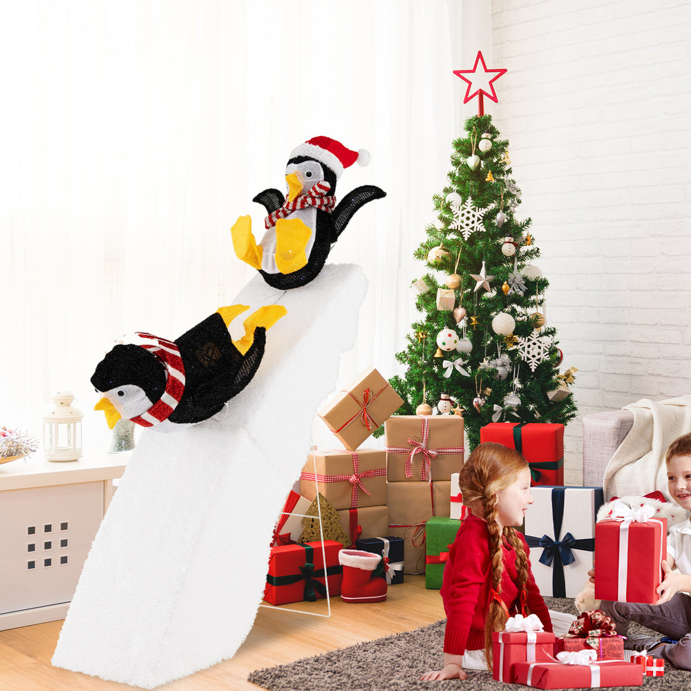 Cheerful 4 feet Christmas penguin decor on a snowy slide, showcasing unique designs and bright LED lights for festive.