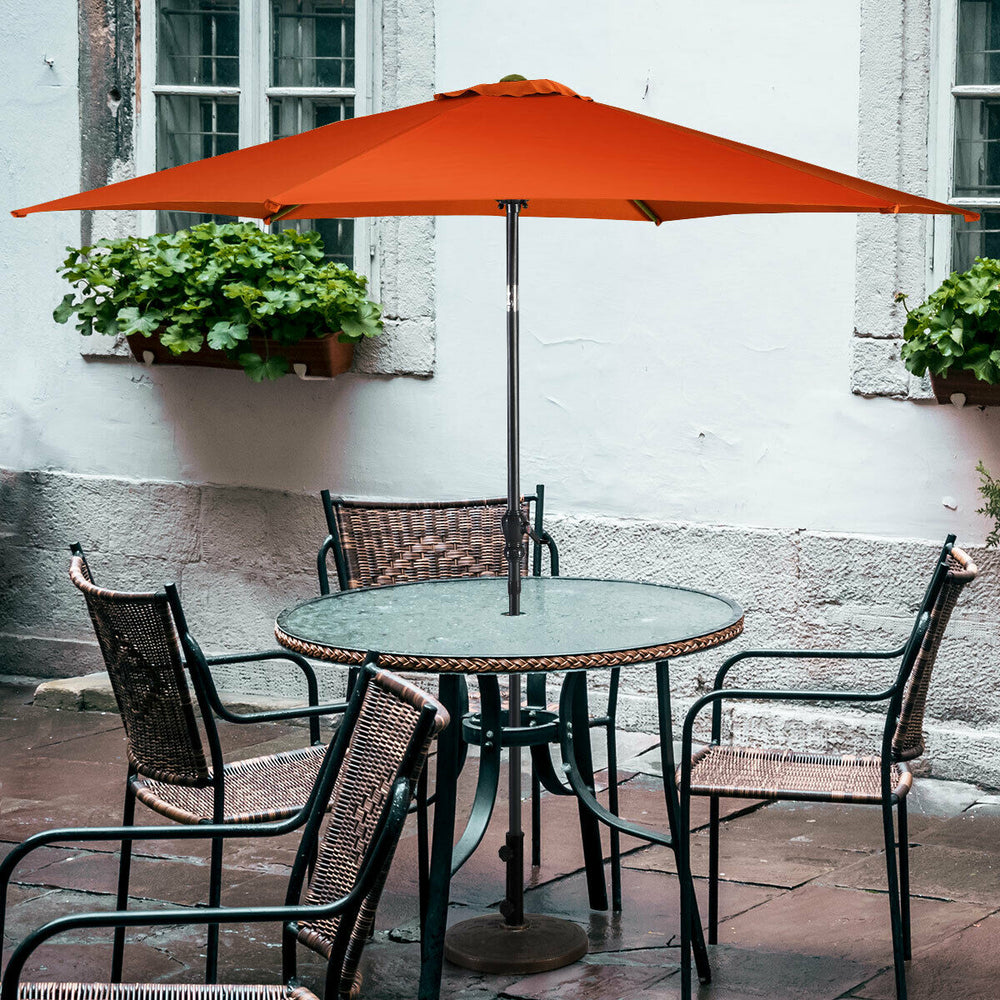 9 ft orange patio umbrella with crank above a round table, providing shade for outdoor dining and relaxation.