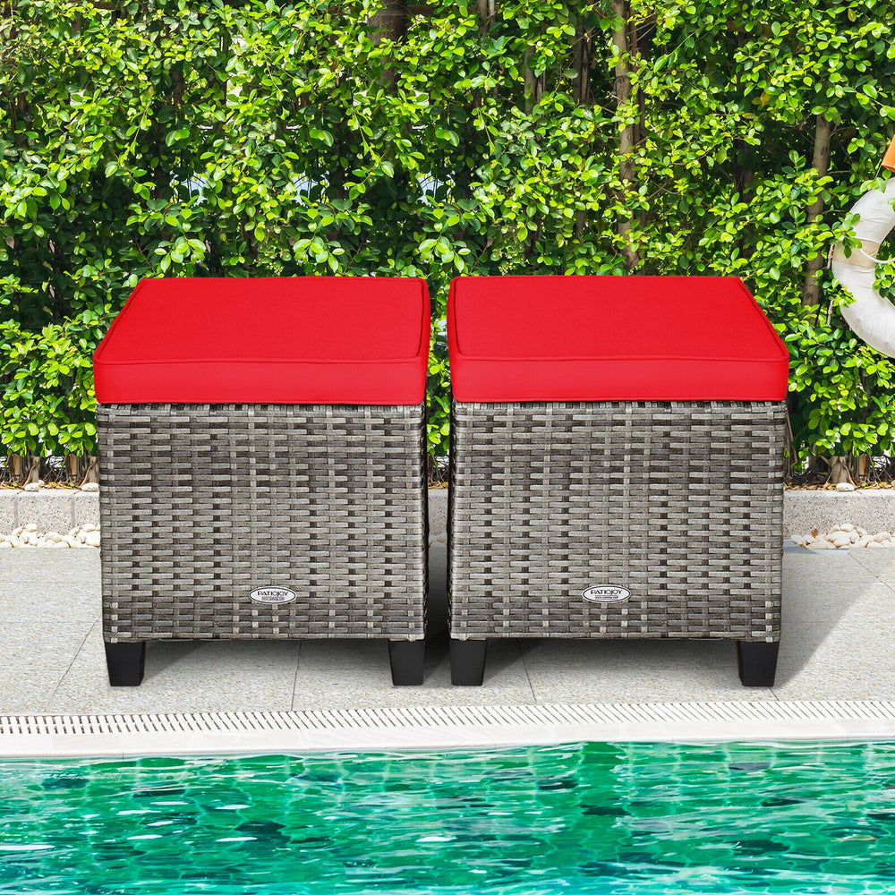 Two outdoor rattan ottomans with red removable cushions, perfect for patio or poolside relaxation and comfort.
