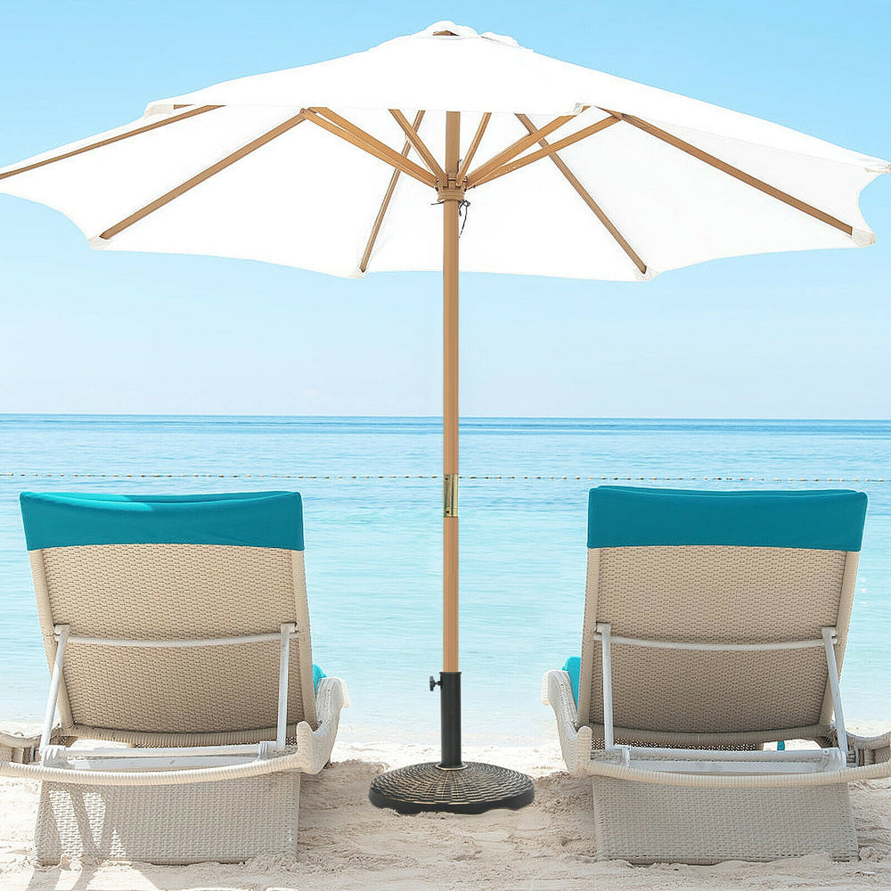 Patio market umbrella base stand with rattan design, featuring a durable resin material for stability by the beach.