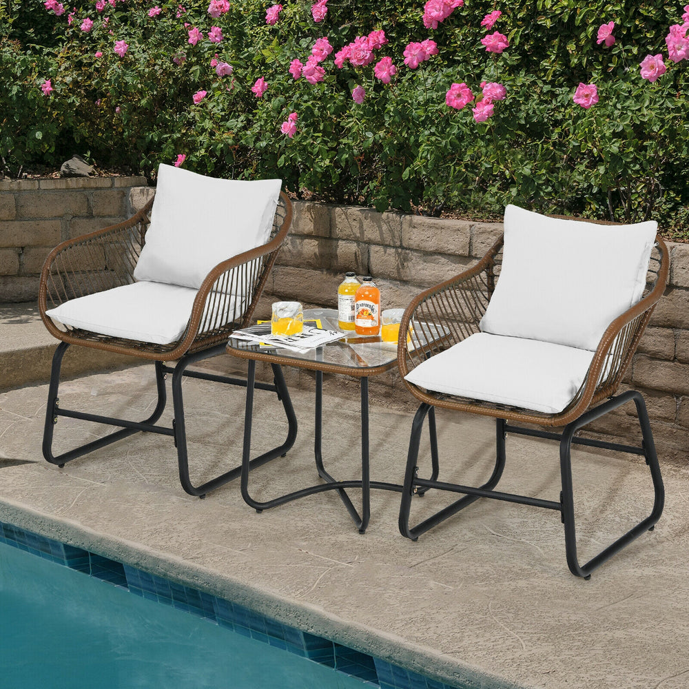 Two cushioned armchairs and a glass table in a patio setting, featuring weather-resistant PE rattan for outdoor.