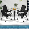 Four stackable black patio dining chairs with armrests, featuring ergonomic design and lightweight structure for.