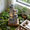 Four-tier outdoor water fountain with cascading bowls and LED lights, creating a calming ambiance for relaxation.
