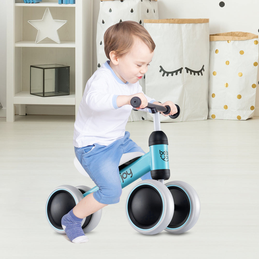 Toddler riding a blue baby balance bike with 4 wheels, designed for stability and motor skills development.