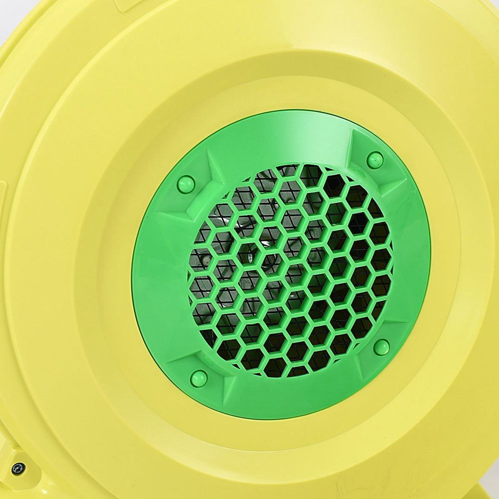 Close-up view of the green and yellow air blower pump fan with a honeycomb vent, designed for inflatable bounce houses.