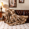 Soft plush fuzzy luxury faux raccoon fur blanket draped over a brown sofa, ideal for cozying up on chilly nights.