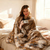 Luxurious 540GSM faux raccoon fur blanket draped over a bed, offering warmth and softness for cozy relaxation.