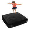 Child jumping on a 57 x 57 inch black crash pad sensory mat, filled with foam blocks for safe play and sensory.