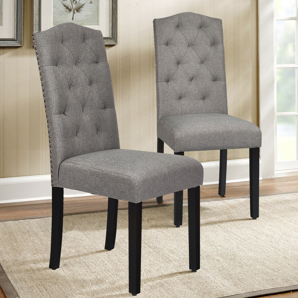 Single gray tufted upholstered dining chair featuring a high curved backrest and elegant rivet design, perfect for.