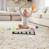 Child playing with a 32-note glockenspiel xylophone on a carpet, surrounded by colorful toys in a cozy living room.