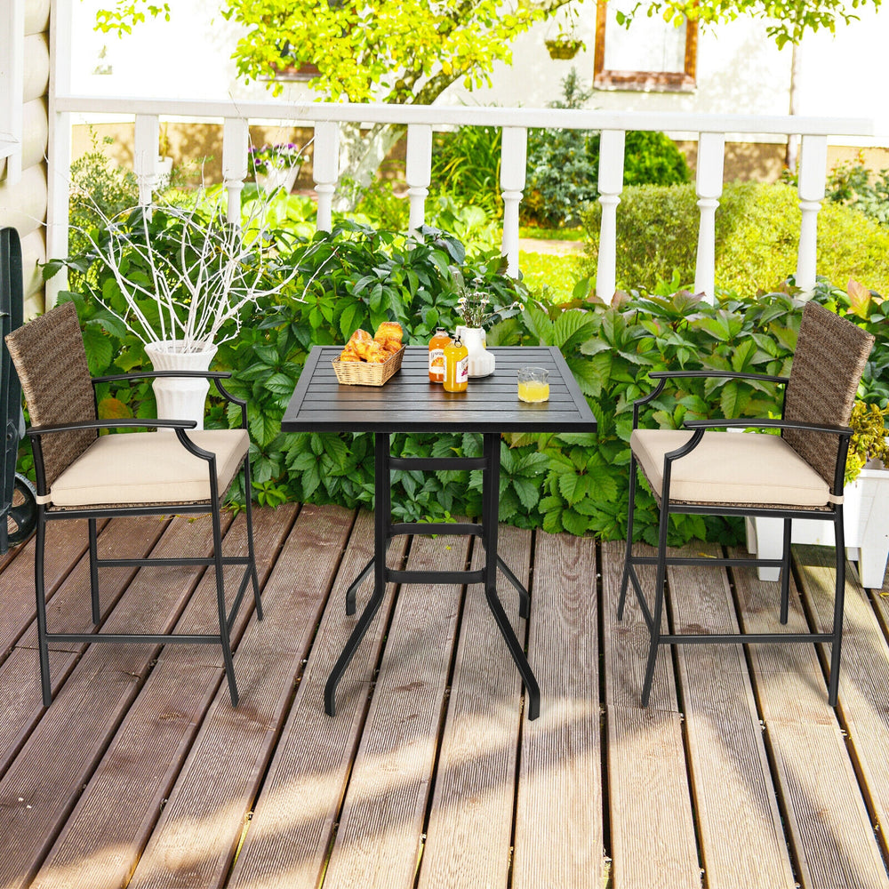 Outdoor rattan bistro set featuring a bar table and two cushioned stools, perfect for poolside relaxation.
