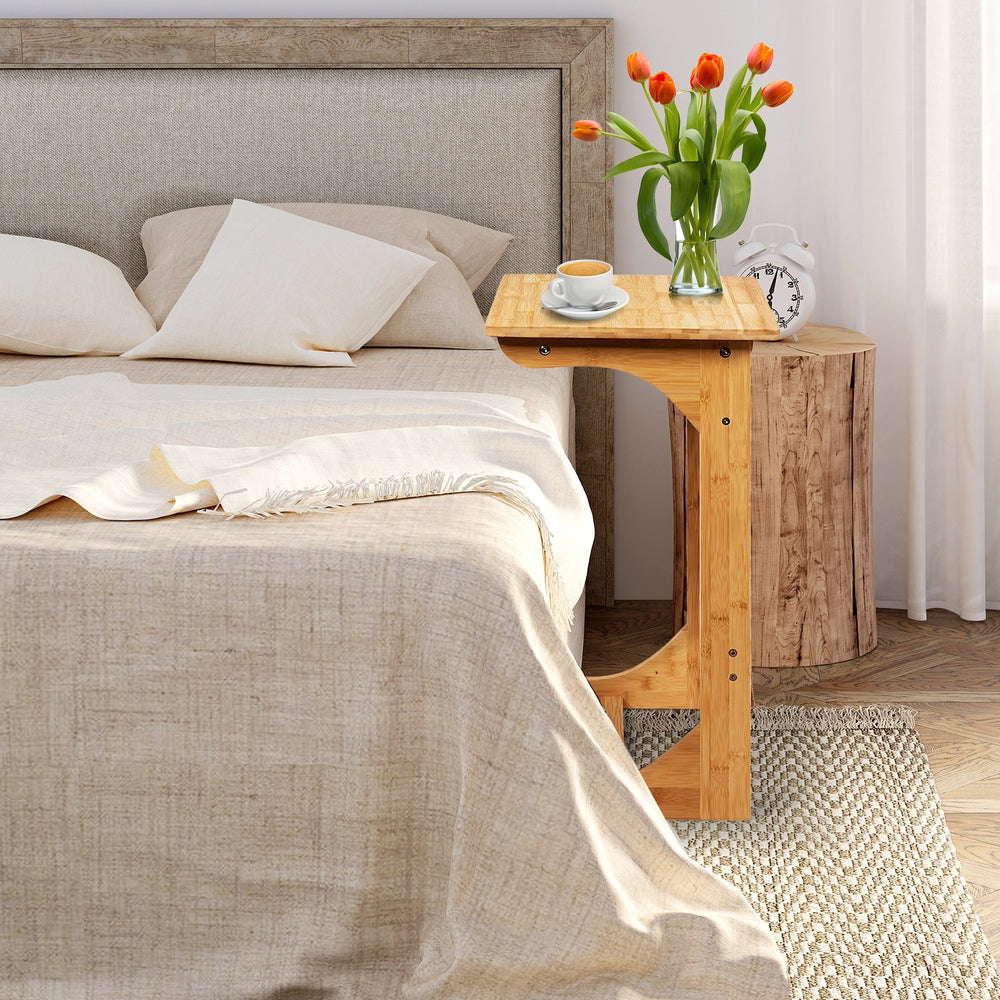 Bamboo bedside table with storage bag, featuring round corners, ideal for saving space beside a bed or sofa.