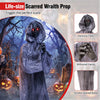 Life-size weeping woman animatronic with tattered smoke-stained robes and piercing red eyes for a haunting Halloween display.