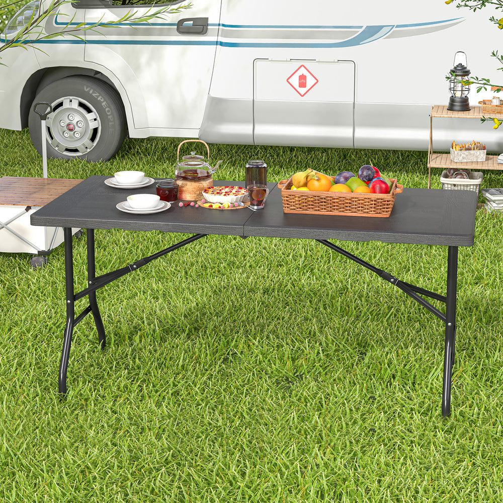 5FT folding picnic table with wood grain HDPE tabletop, set outdoors with food and drinks, ideal for gatherings.