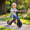 Toddler riding a blue 5-in-1 balance bike on a path, featuring removable pedals and adjustable handlebars for comfort.