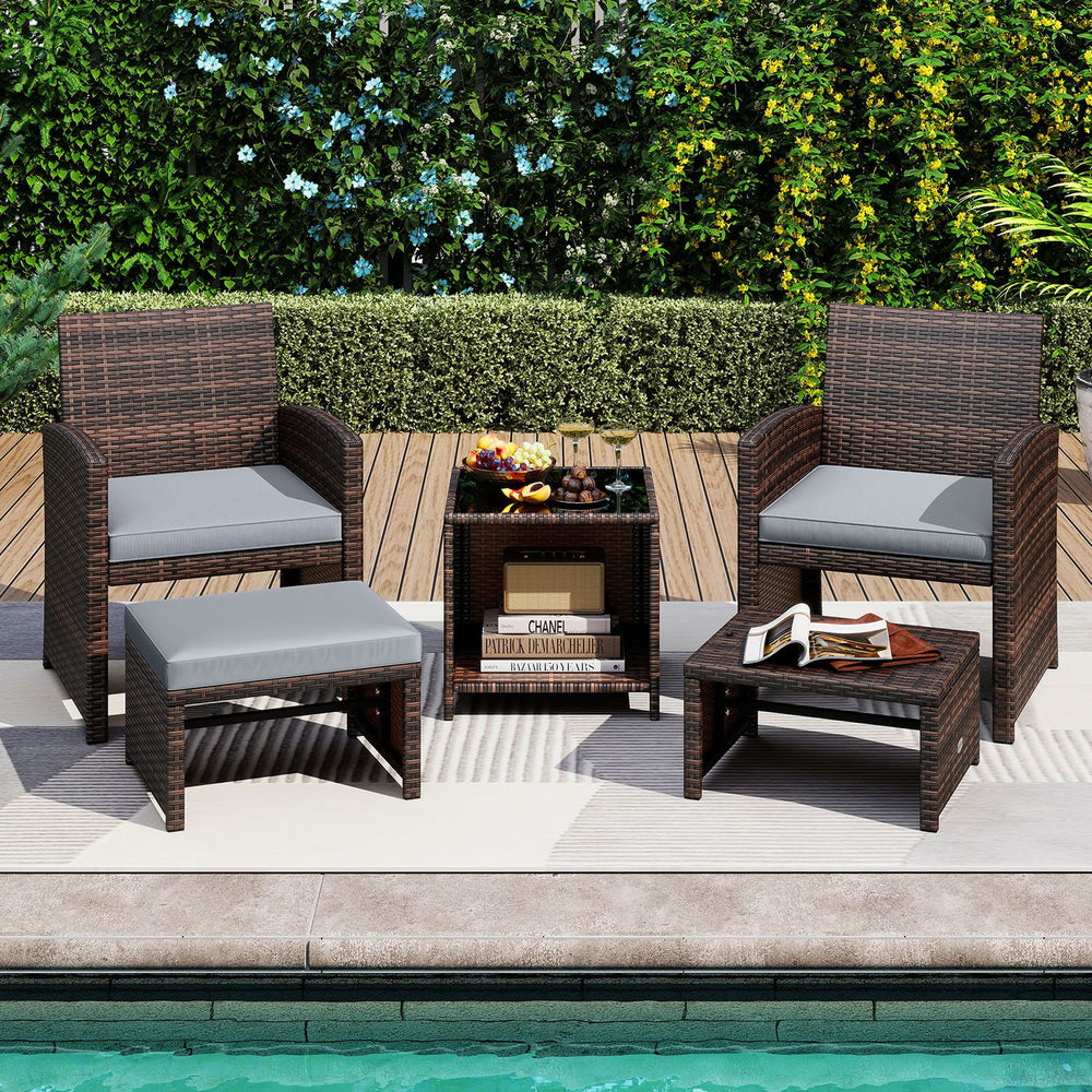 Patio rattan furniture set featuring gray cushions, tempered glass coffee table, and versatile ottoman for outdoor relaxation.