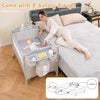 Portable baby beside sleeper bassinet in beige with changing station, safety straps, and side storage pockets for.