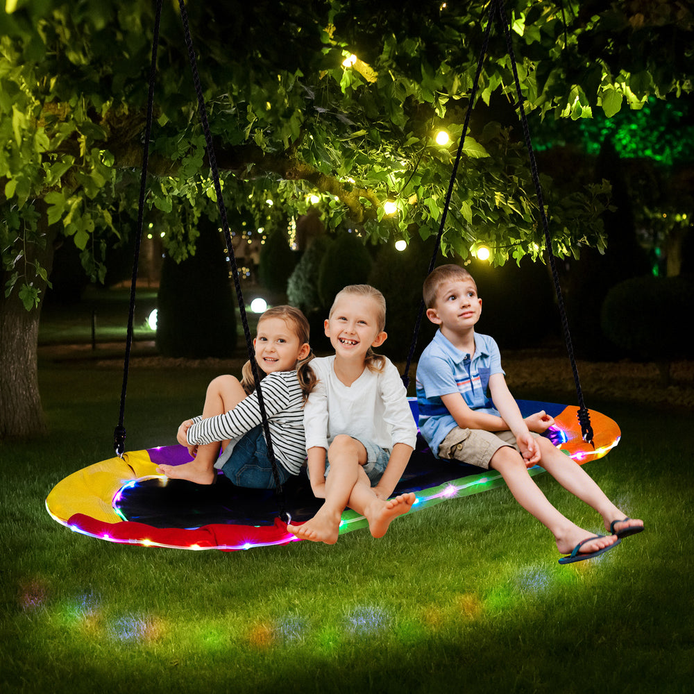 Colorful 60-inch saucer swing with LED lights, featuring kids enjoying nighttime play in a garden setting.