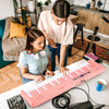 61-key foldable pink piano keyboard with MIDI function, dual keyboard, and wood grain surface for comfortable playing.