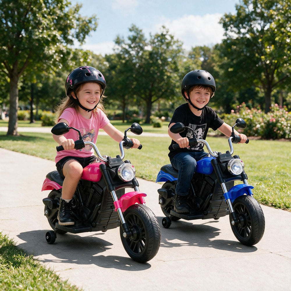 Two kids riding a pink and blue 6V motorcycle with detachable training wheels in a park, designed for ages 2-5.