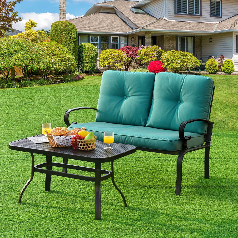 Turquoise cushioned loveseat and coffee table set on a green lawn, perfect for outdoor patio relaxation.