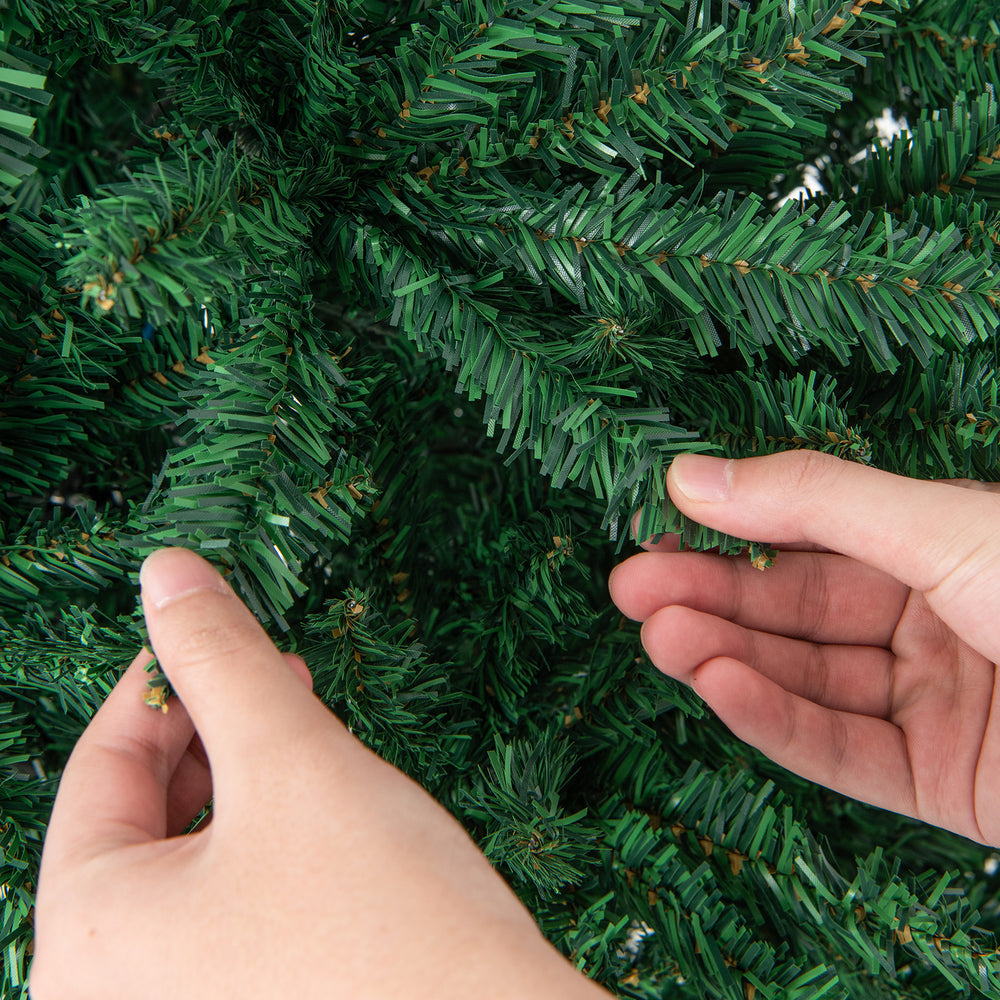 Close-up of hands adjusting the branch tips of a 6 feet hinged artificial Christmas tree with a solid metal stand.
