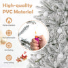 Close-up of a hand holding a lighter near a snow-flocked artificial Christmas tree made of flame-retardant PVC material.