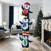 Three stacked penguins with Christmas hats and scarves, illuminated by cold white LED lights for festive holiday decor.
