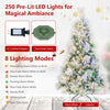 6 ft flocked pine Christmas tree with colorful pre-lit LED lights and folding metal stand displayed in a snowy scene.