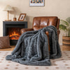 Soft plush gray faux wolf fur blanket draped over a leather armchair, perfect for cozying up by the fireplace.