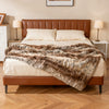 Soft plush fuzzy luxury faux raccoon fur blanket draped over a bed, ideal for warmth and comfort in any setting.