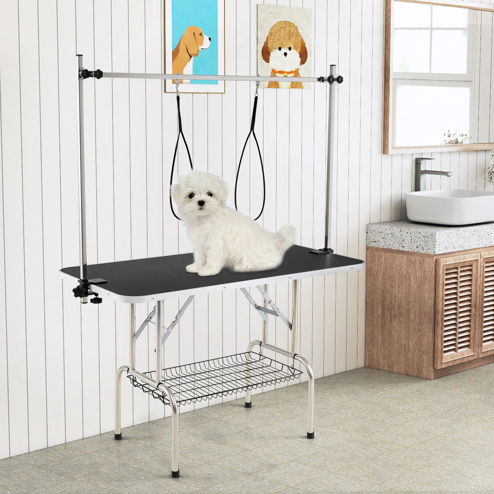 Foldable dog grooming table with height adjustable arms, non-slip waterproof surface, and storage mesh tray for pet.