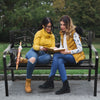 Two women reading on a 50-inch patio bench with a steel frame and cast iron backrest, perfect for outdoor relaxation.