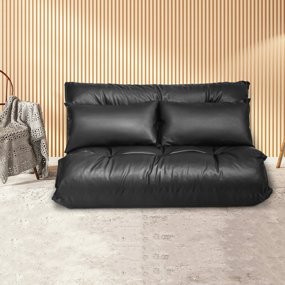 Black foldable PU leather leisure floor sofa bed with two pillows, adjustable for lounging or sleeping in small spaces.
