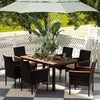 Stackable rattan dining chairs with cream cushions around a rectangular acacia wood table, ideal for outdoor gatherings.