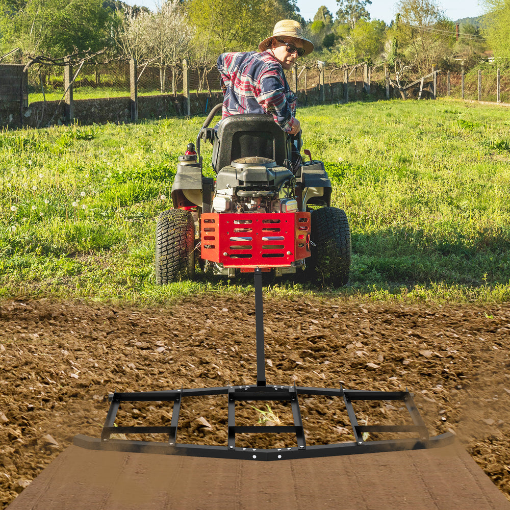 84-inch driveway drag tow behind landscape leveling rake, shown in use on a farm, effectively leveling soil and gravel.