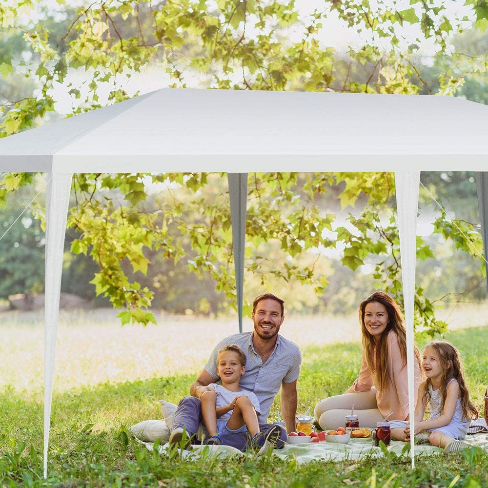 10 x 20 feet waterproof canopy tent in bright white, providing shade for a family picnic in a lush outdoor setting.