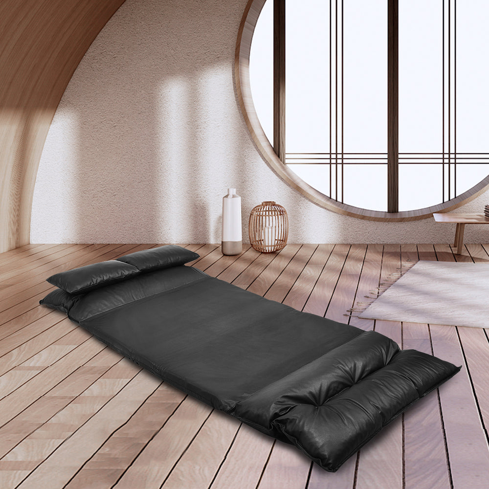 Foldable black PU leather leisure floor sofa bed with two pillows, adjustable for reading or relaxing in small spaces.