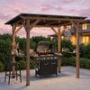 Cedar wood BBQ gazebo with a sloped metal roof and two side serving shelves, ideal for outdoor gatherings and parties.
