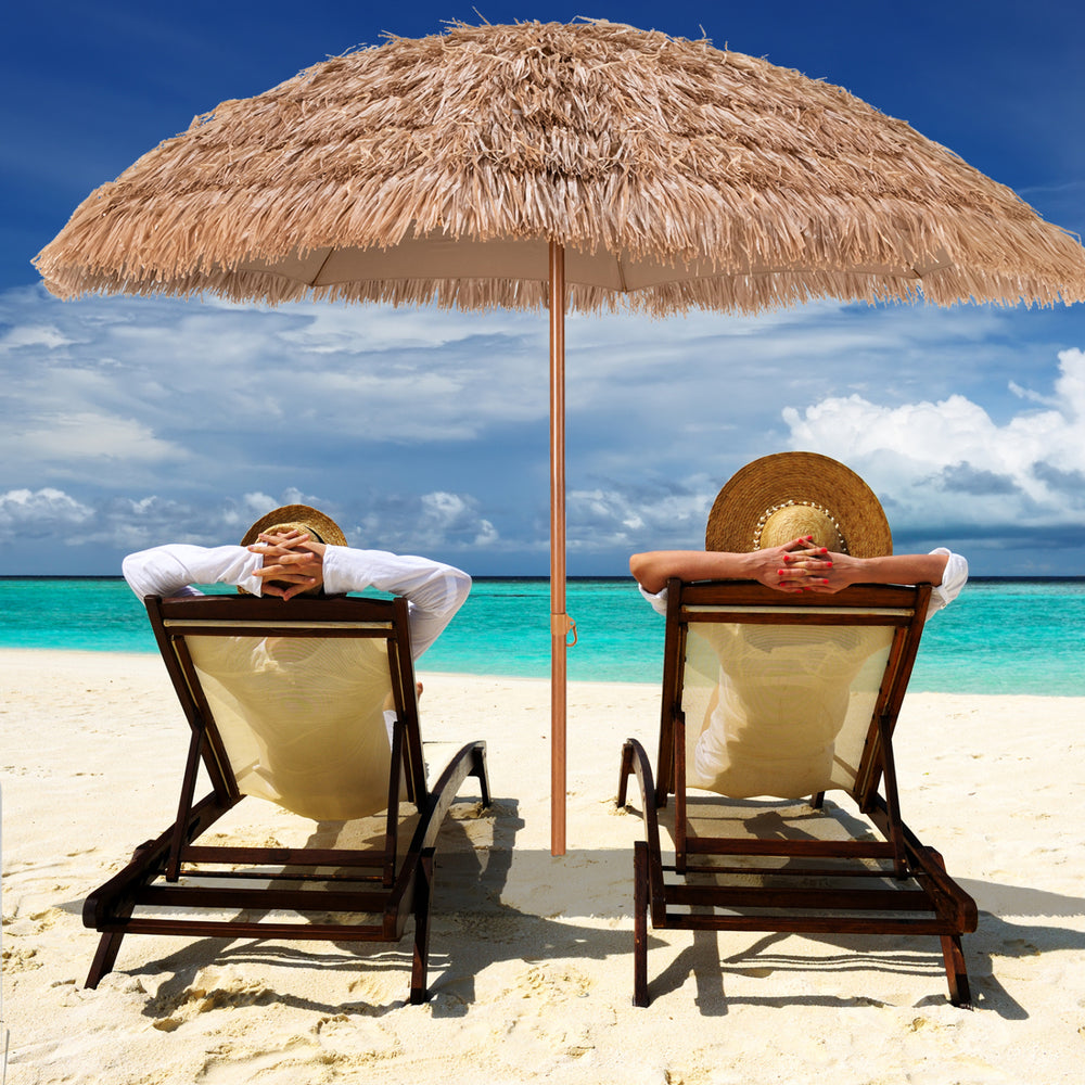 Thatched tiki umbrella providing shade on the beach, featuring durable polyester fabric and a tropical Hawaiian design.