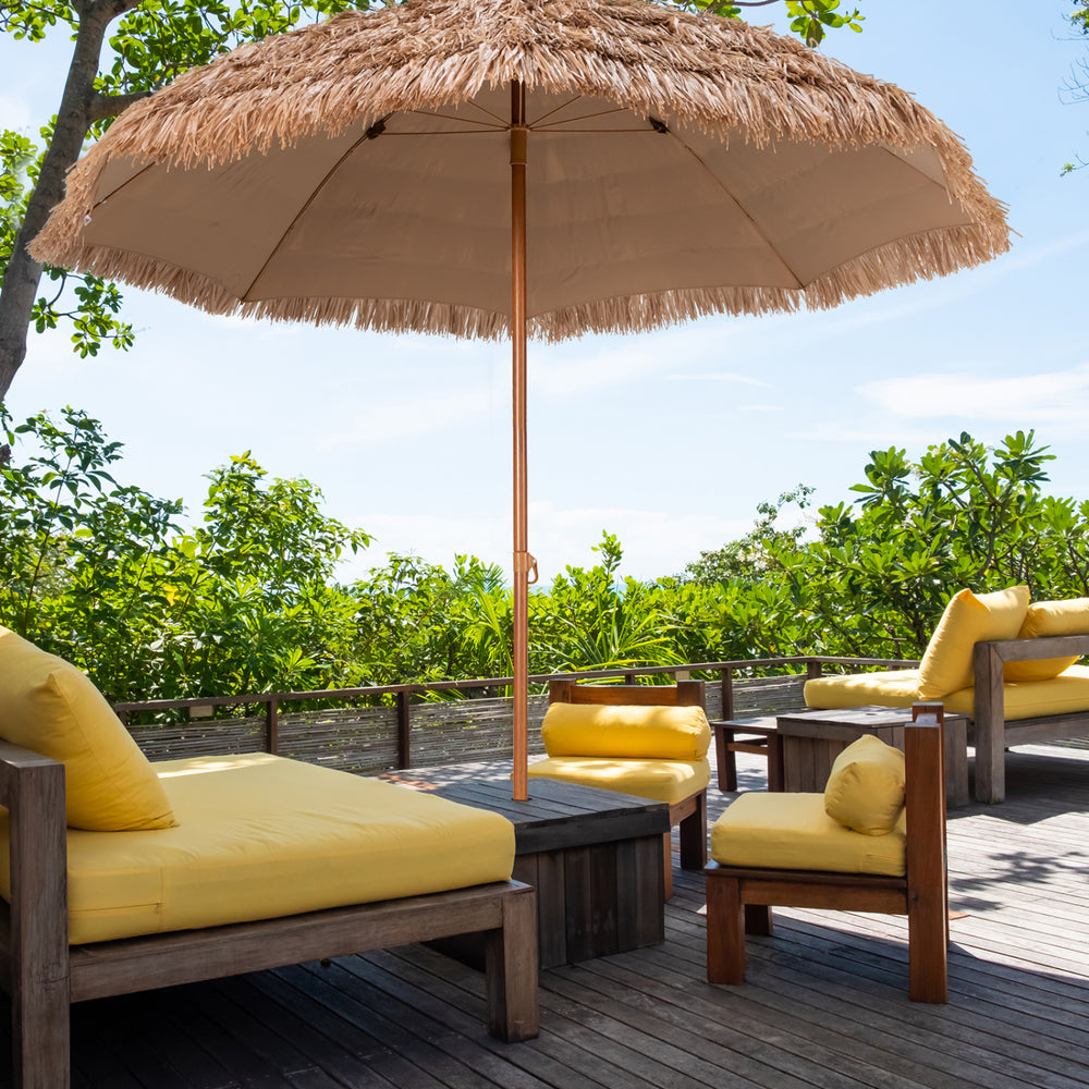 Thatched 8-foot patio umbrella with yellow cushions, providing sun protection for outdoor relaxation in a tropical.