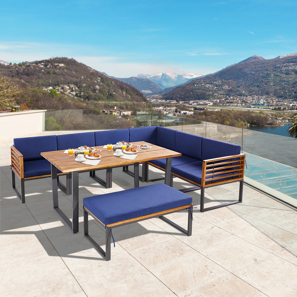 Acacia wood patio dining set with navy cushions, featuring a table, ottoman, and comfortable seating for outdoor use.