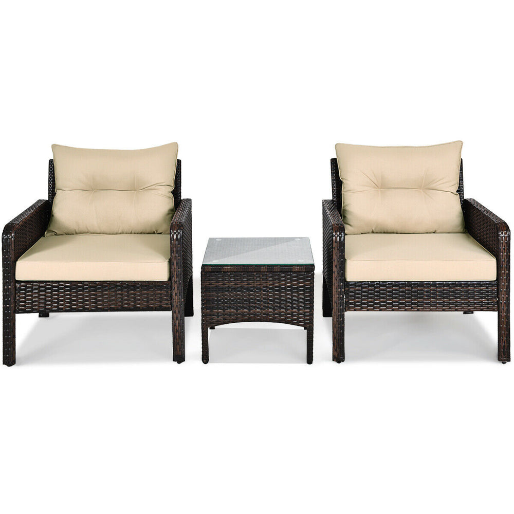 Two beige cushioned rattan chairs with a glass-top table, perfect for outdoor patio relaxation.