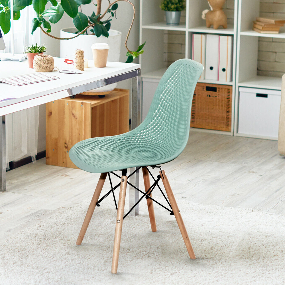 Modern green plastic hollow chair with wood legs, featuring a curved backrest for ergonomic support, ideal for dining.