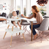 Convertible high chair in white with solid wood legs, featuring a baby seated and enjoying a meal at the dining table.