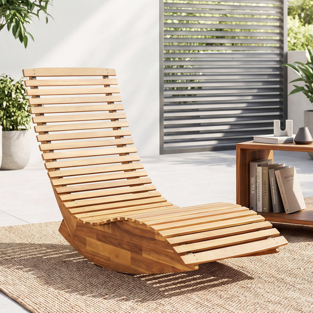 Acacia wood rocking patio lounge chair features a slatted design and ergonomic shape for optimal comfort and relaxation.