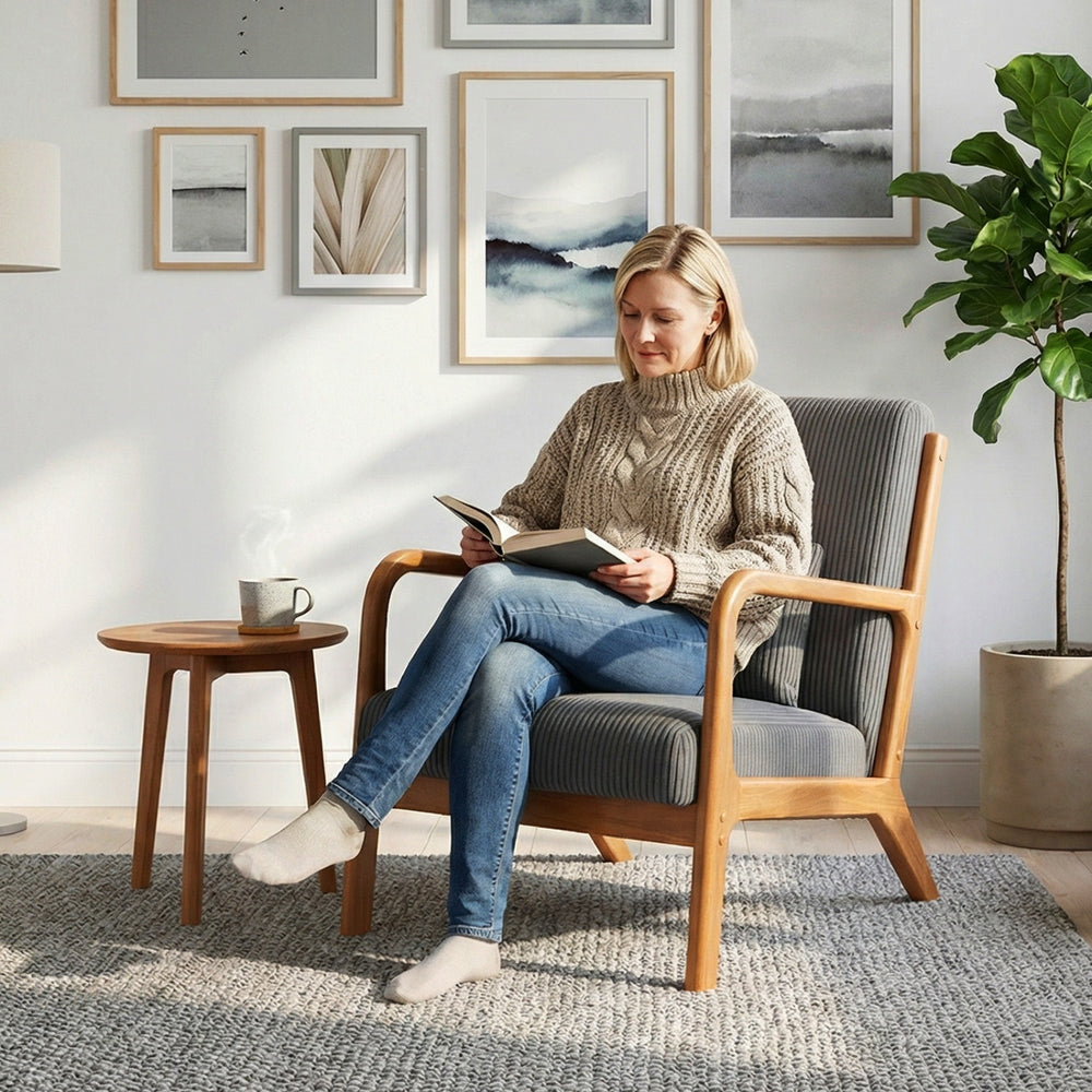 Accent chair with gray corduroy upholstery, lumbar pillow, and solid wood frame, ideal for cozy reading spaces.